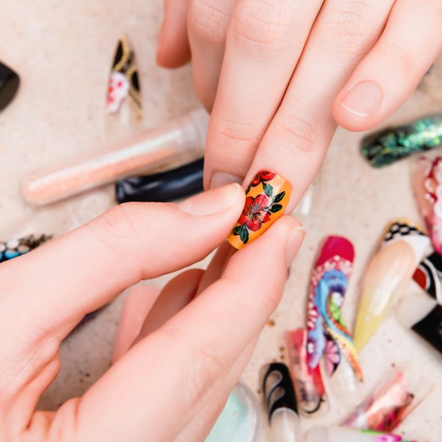 Girl trying artificial nails tips with flower nail design