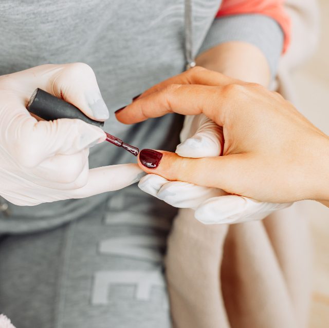 woman-receiving-manicure-from-woman-gloves-mask-beauty-salon-during-daytime